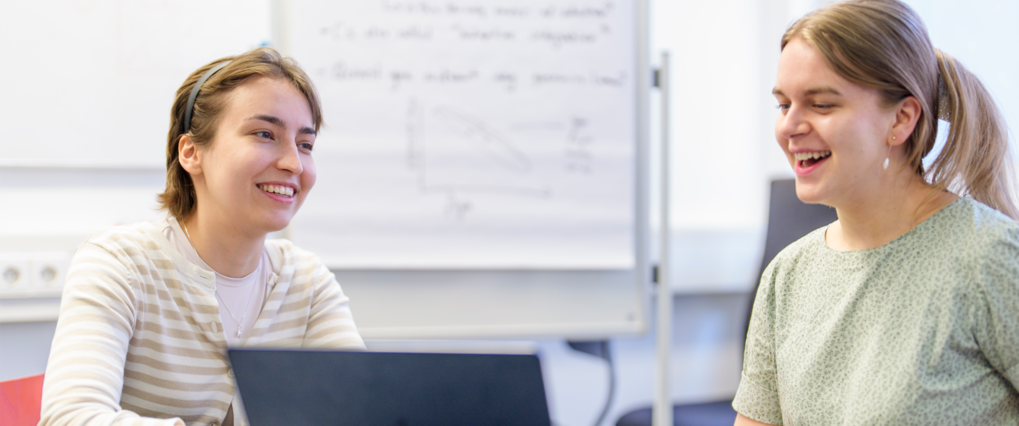 Two students sitting in front of a computer discussing 